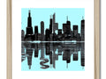 A wooden framed piece of art hanging on a wall decorated with the city skyline of Chicago