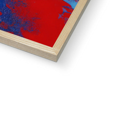 A large piece of blue and red artwork in a wooden frame on a white table.