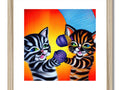 Two cats in striped cat print are lying on top of a picture frame.
