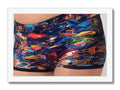 Two men that are wearing colorful swimming trunks and a top with a fish on the
