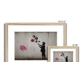 Two photo frames hanging on a wall with spray sprays of white flowers.