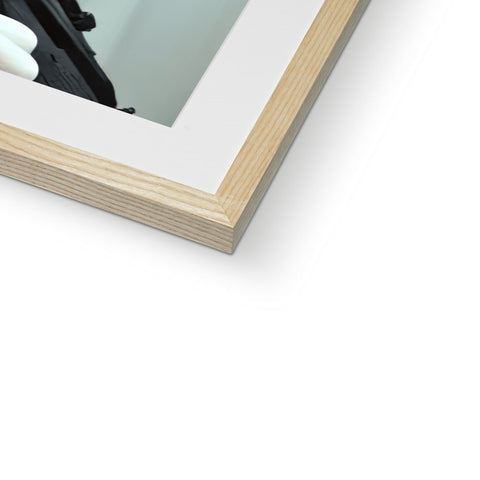 A picture framed wooden frame on top of a white wall next to a mirror.