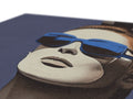 A dark blue pair of sunglasses, hanging with an image of a blue blanket.