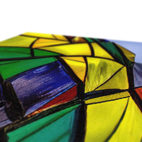 A stained glass picture of rainbow umbrella hanging from a table.