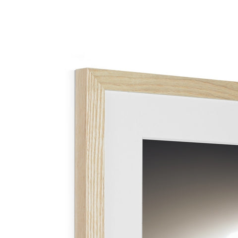 A frame is made from pine on a mirror next to a large white chair.