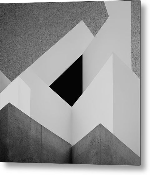 An art print with the shape of two triangles on a brick wall.