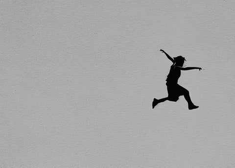 A person is jumping skateboarding in the air above a wall from the sky,