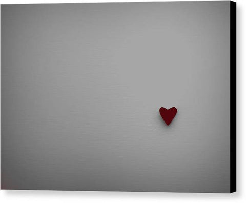 A red heart with a black pillow on top of a white art print