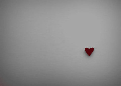A heart is placed beside a piece of paper and a white background.
