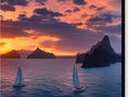 A sunset with sailboats floating on a large bay with lots of water