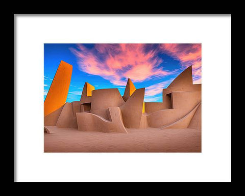 A piece of art print on a desert beach next to some buildings