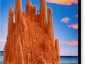 An orange statue in a castle surrounded by sand in a sandfilled ocean