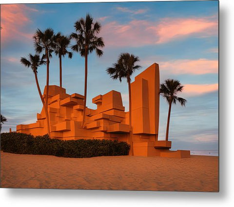 A beach with a sculpture in it that has an orange background image of Santa Monica