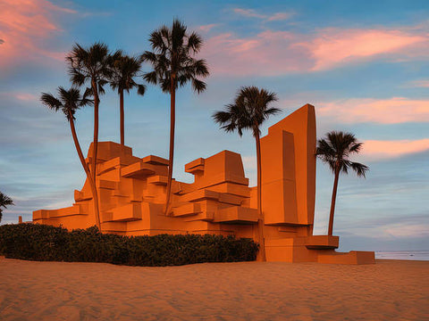 The beautiful sculpture of a castle sitting on a beach with palm trees above it