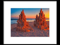 An art print with a close up of a sand castle behind a river