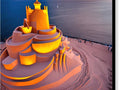 A colorful image of buildings that are illuminated inside of a sand castle