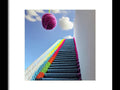 A colorful art print hanging on the wall beside a staircase leading up to a staircase