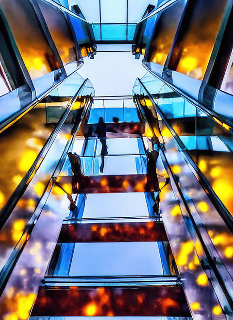 A person going up an escalator on a building with a ladder above them